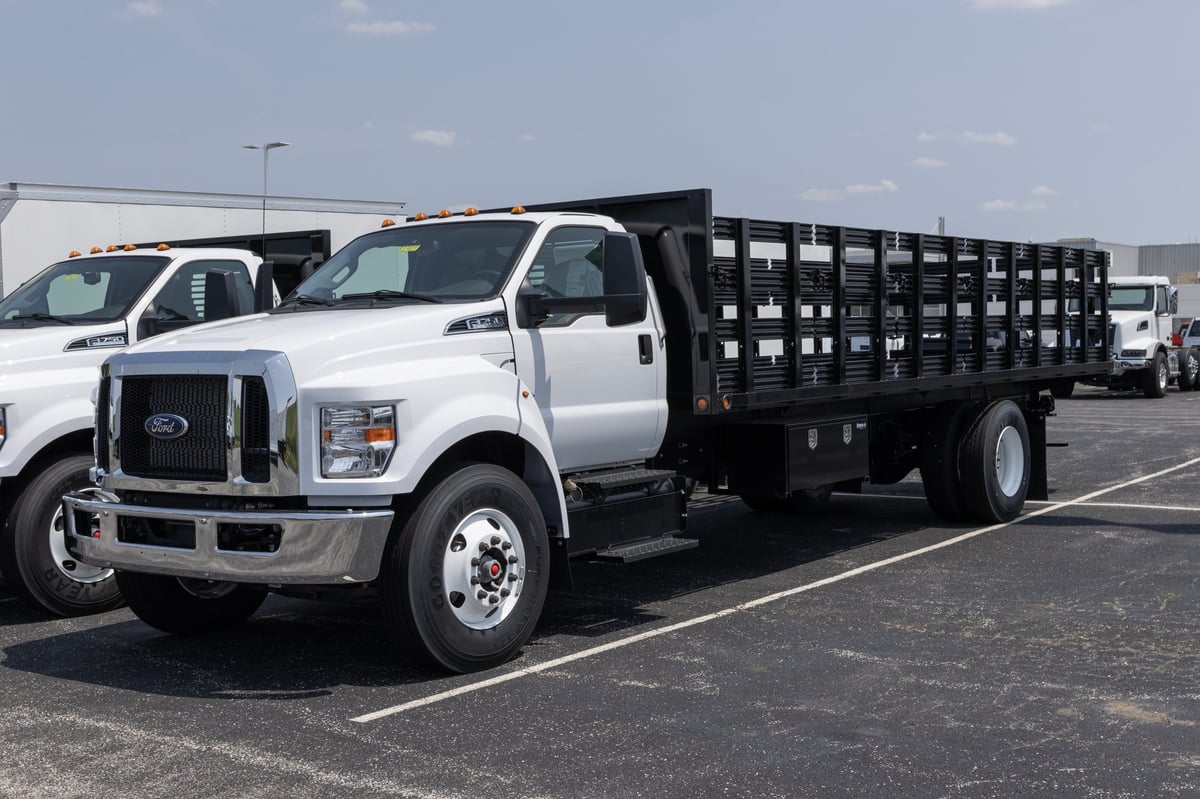 Ford F-750 stake bed truck hauling furniture